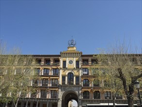 Yellow building with arcades and many windows under a blue sky, toledo, spain