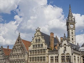 Row of gothic buildings with ornate facades under a clear blue sky with clouds, skyline of a