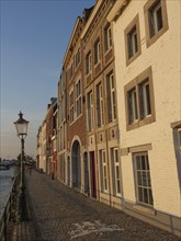 Narrow alley with cobblestones and historic houses, illuminated by evening light, Maastricht,
