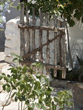 Old rustic wooden gate next to stone wall and green vegetation, ibiza, Spain, Europe