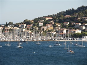 A multitude of boats and houses along a coastline surrounded by green hills and blue water, la