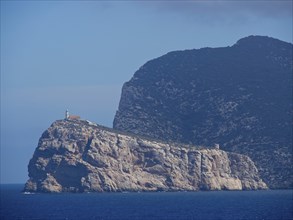 A large rock by the sea with a blue sky in the background, palma de mallorca on the mediterranean