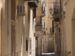 A narrow alley between historic buildings with shutters and balconies in a quiet atmosphere,