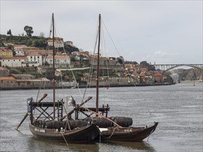 Historic boats on a river with hill and bridge in the background, quiet and old atmosphere,
