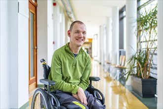 Portrait of a smiling caucasian young disabled man in wheelchair in the university