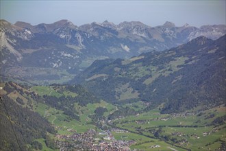 Panoramic view of a mountain landscape with a village and green meadows in a wide valley, Mountain