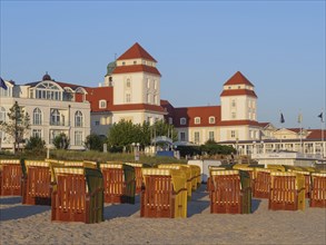 Historic buildings on the sandy beach with numerous beach chairs in the evening light, autumn