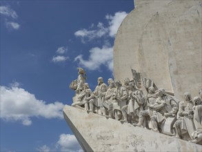 Large stone sculptures of several figures on a monument in front of a blue sky, Lisbon, Portugal,