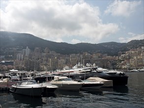 A harbour full of yachts against the backdrop of a city under a cloudy sky, monaco on the French