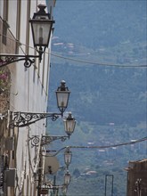 Street lamps in front of a mountain landscape with distant buildings, conveys a historical and