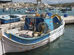 A fishing boat with various items of equipment in the harbour, many colourful fishing boats in a