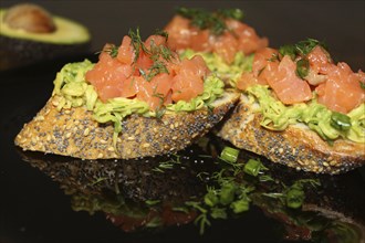 Gourmet bruschetta topped with avocado spread, salmon, garnished with dill and chives on a
