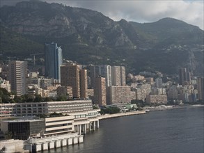 Urban landscape with skyscrapers against a mountainous background, the sea in the foreground, Monte