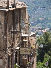 Narrow tram in the old town, lamps and signs for a restaurant, nature and mountains in the