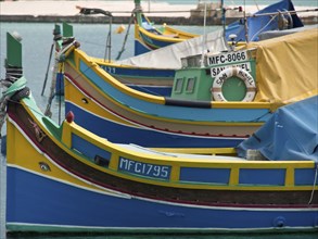 Close up of colourful fishing boats in the water, with bright colours and ropes, many colourful