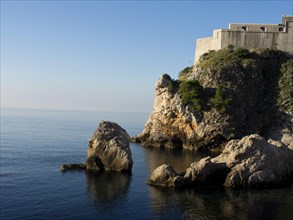 Historic fortress on a rocky coastline overlooking the sea under a clear blue sky, the old town of