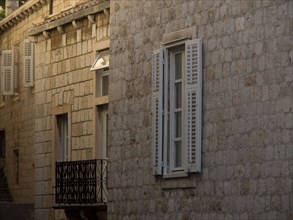 Stone buildings with closed windows and balconies, the old town of Dubrovnik with historic houses,