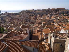 View over the terracotta roofs of a historic city by the sea, sunny atmosphere, the old town of
