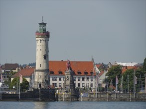 A lighthouse and a statue at the harbour, surrounded by historic buildings and water, view of a