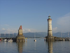 Panoramic view of the harbour with a lighthouse and lion sculpture under a blue sky, towers at a