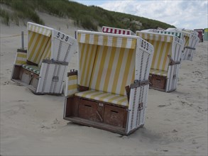 Several beach chairs on the sandy beach with dunes in the background, the north sea island baltrum