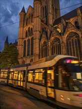 Moving tram in front of a gothic cathedral at dusk in a historic city, historic buildings with