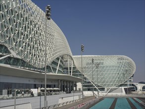 Building with modern grid structure, large windows and racetrack under blue sky, Abu Dhabi, United