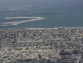View of a coastal town with desert sand and the ocean in the background by day, Dubai, Arab