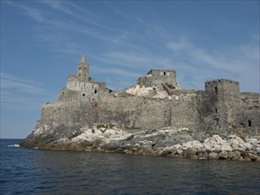 Historic castle on a cliff by the sea, towering imposingly over the sea, with a clear blue sky,
