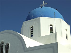 White church with blue dome and cross in front of a clear blue sky, The volcanic island of