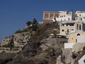 Houses and terraces clinging to the cliffs under a blue sky, The volcanic island of Santorini with