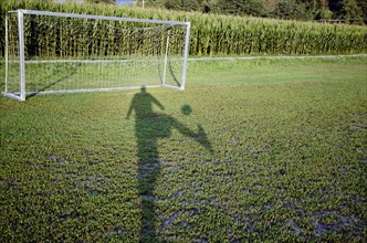 Shadow of a Soccer Player and Playing the Ball to the Goal Close to a Corn Field in a Sunny Day in