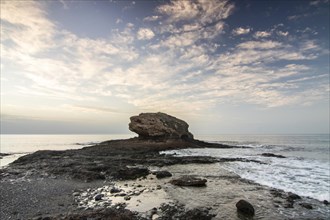 Sunrise with sea view on a rocky coast in warm colours. Landscape with a lava stone beach of