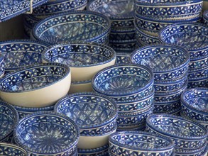 A collection of blue ceramic bowls with traditional patterns stacked on a market stall, Tunis in