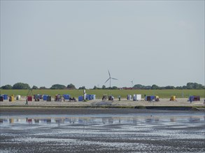 View of a coastal landscape with colourful beach chairs and wind turbines, Baltrum Germany