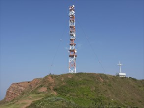 A large transmission mast stands on an overgrown hill under a clear sky. A technical highlight in