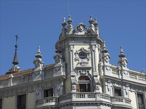 Magnificent white baroque-style building with small towers and blue sky in the background, Madrid,