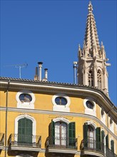 Yellow building with gothic tower and blue shutters under a clear sky, palma de mallorca on the
