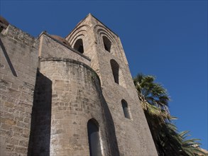 Historic church building with round towers and palm trees in the sunshine, palermo in sicily with