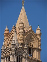 Close-up of a gothic church tower with ornate architecture under a blue sky, palermo in sicily with