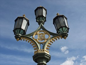 Artistic lantern with golden decorations against a blue sky with white clouds, London, England,