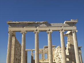 Ancient ruins with columns and partially preserved building under a clear blue sky, Ancient