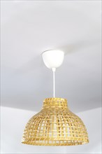 Natural wicker chandelier on the ceiling of a house with white walls