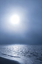 Morning sun shining through the dense fog reflecting on the waters of the Biloxi Bay at Front Beach