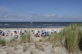 Beach with numerous beach chairs, behind it the sea under a blue sky with some clouds, Spiekeroog,