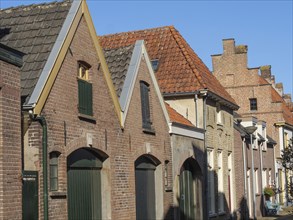 Historic terraced houses with red tiled roofs under a clear blue sky, red brick houses and churches
