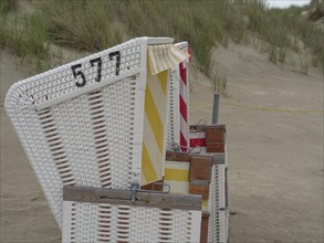 Side view of a beach chair with the number 577 on the sandy beach next to the dunes, Baltrum