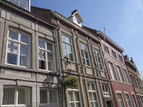 Historic buildings with large windows and flower boxes in bloom under a clear sky, Maastricht,