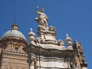 Baroque church structure with dome and stone statue holding a cross, palermo in sicily with an