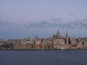 Panorama of the city at dusk with a view of historic buildings by the sea, Valetta, Malta, Europe